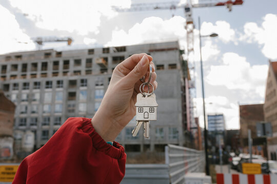 Hand holding a house key in front of a construction site
