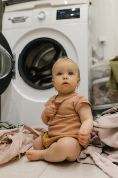 Sitting by the washing machine with laundry during everyday routine