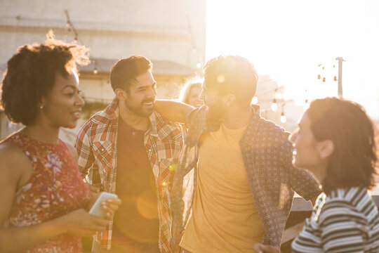 Friends having a rooftop party, chatting and drinking beer