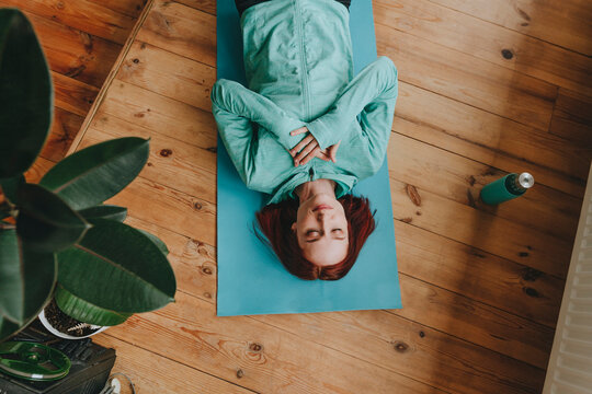 Woman doing meditation with hands on chest lying at home