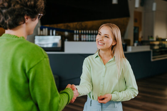 Business colleagues shaking hands and smiling at office meeting