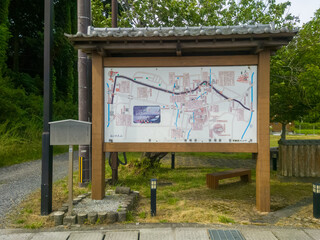 滋賀県甲賀市土山宿の歴史散策ルートを示す木造屋根付きの案内看板。周辺の緑豊かな自然とベンチ、東海道の歴史を感じられる静かな公園の一角を捉えた観光・旅イメージ素材。 © kinomin