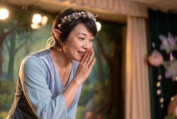 Obraz premium Woman in elf costume wearing flower crown, performing fantasy storytelling on stage