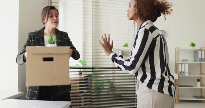 Businesswoman packing box after dismissal in office. Manager debates as items are packed, signaling resignation or fired notice and workplace conflict. Concept of job loss and career change.