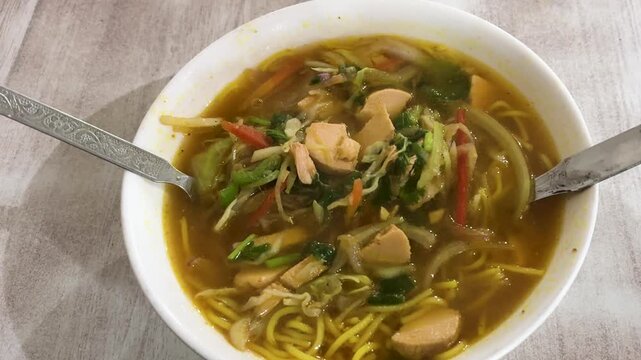 warm bowl of chicken thukpa soup with noodles cabbage carrots and leafy greens