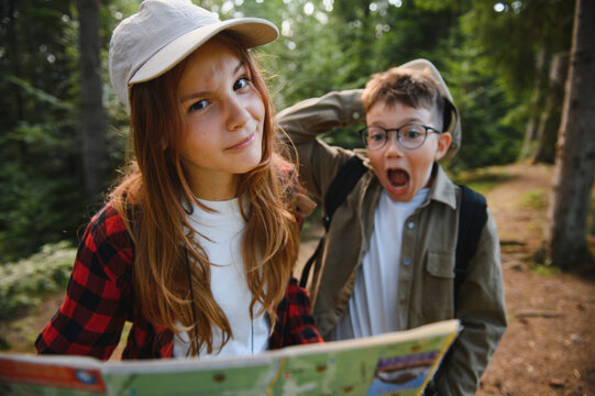 Tourists kids getting lost while hiking in forest, holding map