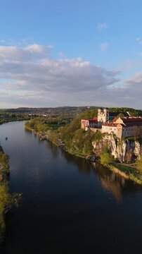Aerial flyover of an abbey on a river in Poland at sunset in spring