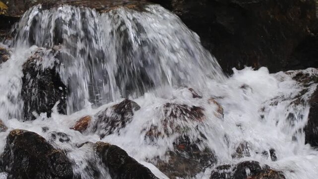 A violent stream of water falls on the rocks in a mountain stream