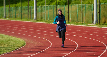 Fototapeta premium Muslim Woman Running on Outdoor Track in Hijab Athletic Wear Training for Fitness and Endurance