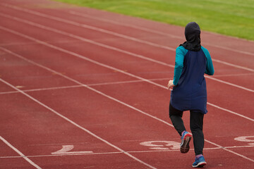 Obraz premium Female Athlete Running on Outdoor Track Wearing Headscarf Training for Fitness and Endurance