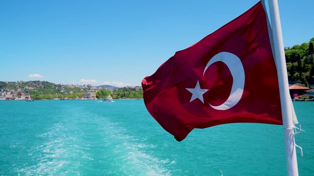 Majestic daytime view of the Bosphorus bridge and strait in Istanbul with the Turkish flag waving proudly.