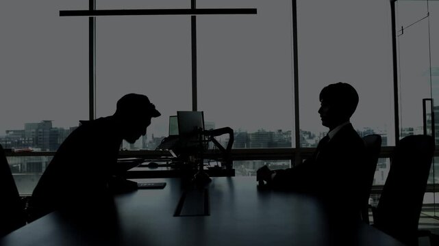 Silhouette of two businessmen shaking hands in a modern office with city view, symbolizing a successful business deal, partnership, or agreement.