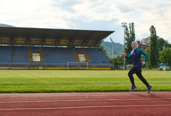 Obraz premium Female Runner In Hijab Training On Stadium Track For Fitness And Healthy Active Lifestyle