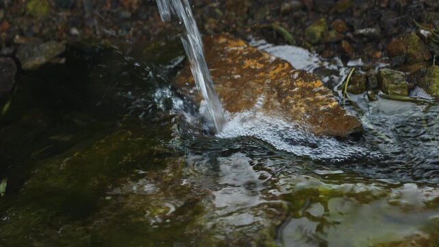 Natural water source, spring. Clean natural water in the mountains, close-up. A water spring with environmentally friendly water.