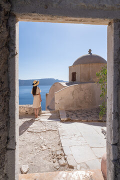 Young woman exploring the ruins of Fort Londsa and enjoying the view of the sea, Oia, Santorini, Greece