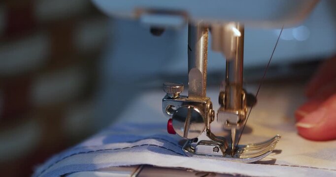 Hands work diligently, sewing blue fabric with a machine. The close-up highlights the precise movements and steady flow of fabric under the needle. 60 fps 4k footage.