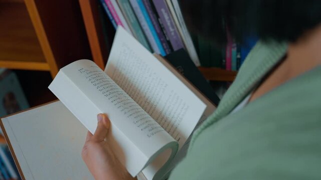 Close-up hand's woman reading book in library.
