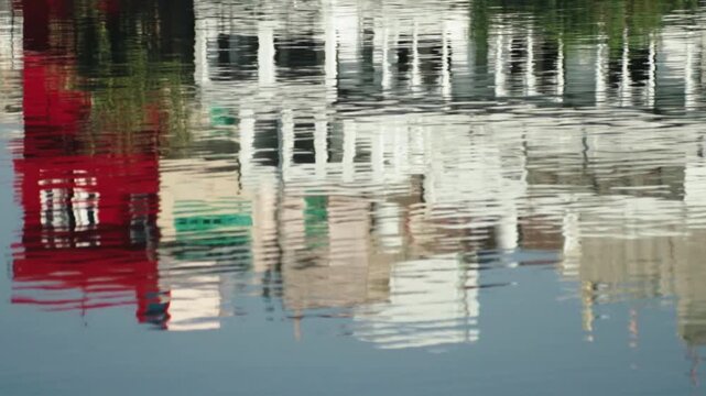 Colorful building reflections rippling on the surface of calm water, creating a mesmerizing and abstract pattern with a peaceful and serene atmosphere, evoking an impressionistic painting