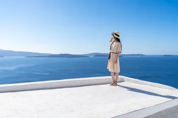 Young woman standing in front of the blue sea, Oia, Santorini, Greece © eyetronic