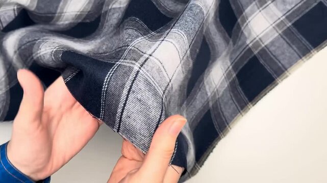 The fabric displays a classic checkered pattern in navy and white hues with a soft texture that holds its shape and provides comfort for various tailored garment projects.