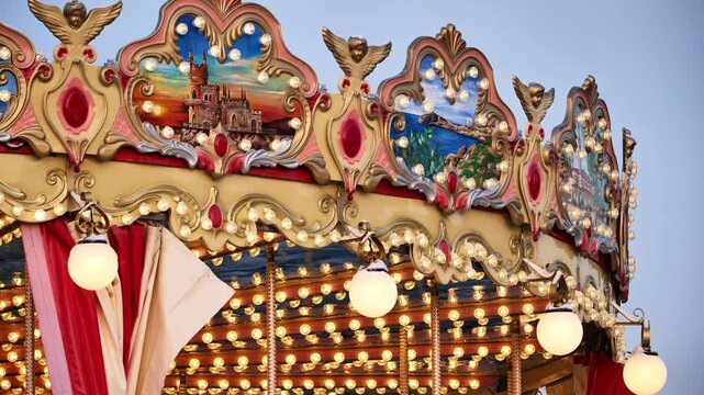 Illuminated vintage carousel top, featuring decorative cherubims and painted landscape scenes
