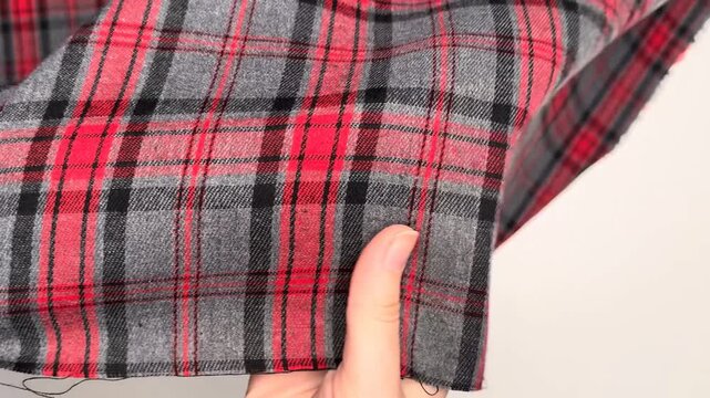 The fabric features a classic checkered pattern in striking red, black, and gray hues with a soft texture that holds its shape and provides comfort for various tailored clothing projects.