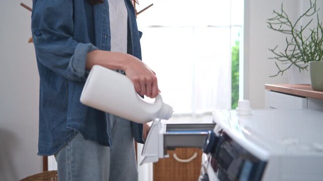 A close-up image of a woman adding laundry detergent to a washing machine