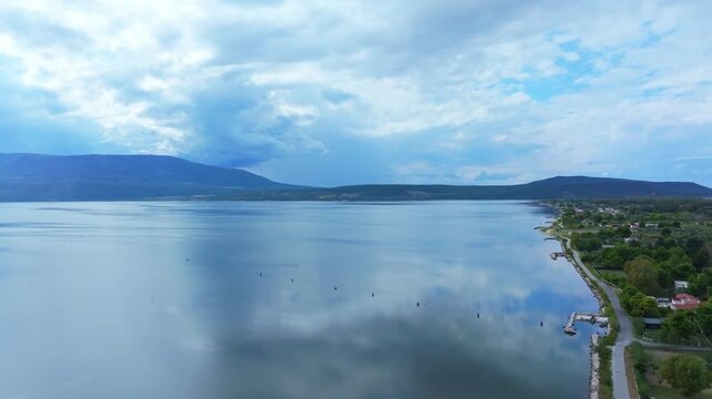 Drone footage captured in September over Lago di Varano in Apulia shows calm lake waters surrounded by mountains beneath dramatic storm clouds.