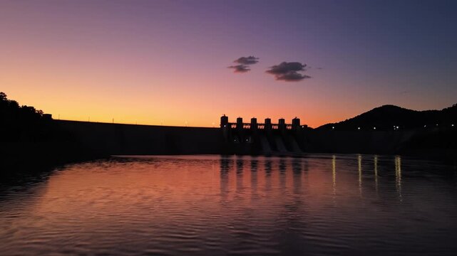 Silhouette dam sunset orange purple sky water reflection calm peaceful landscape with mountain cloud reservoir evening twilight nature horizon scenic reservoir structure outdoor lake dusk calm orange