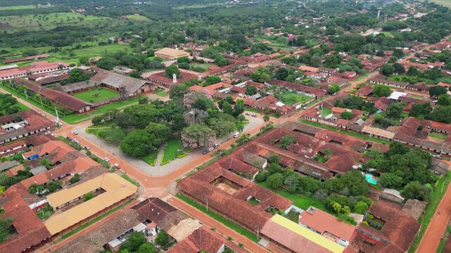 Low aerial orbits green central plaza in small Concepcion, Bolivia