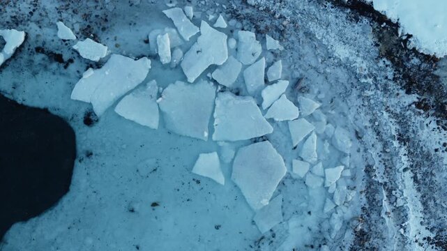Aerial Arctic shoreline with fragmented melting ice along frozen Norway coast, drone