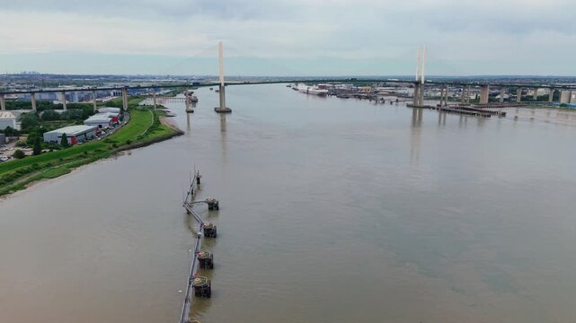 The Queen Elizabeth II bridge spanning River Thames near Dartford with industrial sites on banks, aerial view, UK.