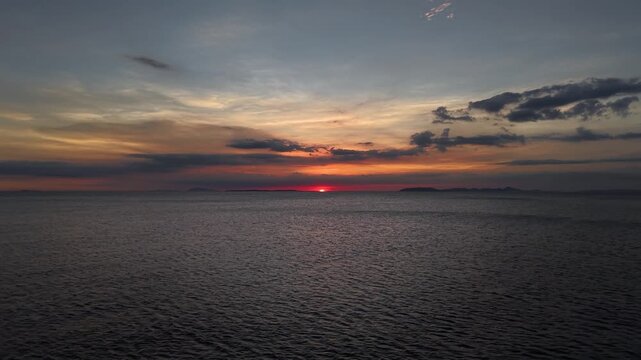 Aerial drone glides smoothly above tranquil waters toward a vibrant sunset, capturing the beauty and scale of a tropical seascape in the Philippines.