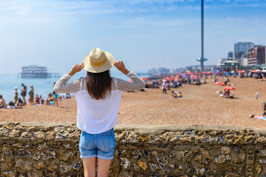 Rear view of a woman looking at the beach of Brighton in East Sussex, England, during a sunny summer day