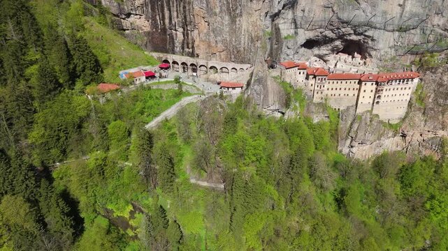 Drone shot of the famous Sumela Monastery built into the sheer rocky mountain cliffs of Trabzon. Historic orthodox Christian heritage site surrounded by lush green forests in Turkey