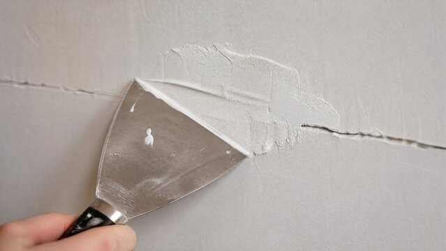 spackle. A stainless steel putty knife smoothing white spackle over a wall crack. safety posters, maintenance manuals, designed for precision metalworking and fabrication facilities.