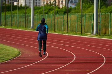 Fototapeta premium Woman in Hijab Running on Outdoor Track for Fitness and Healthy Lifestyle Training
