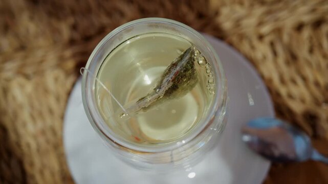 Close up of a tea bag steeping in hot water inside a transparent glass cup