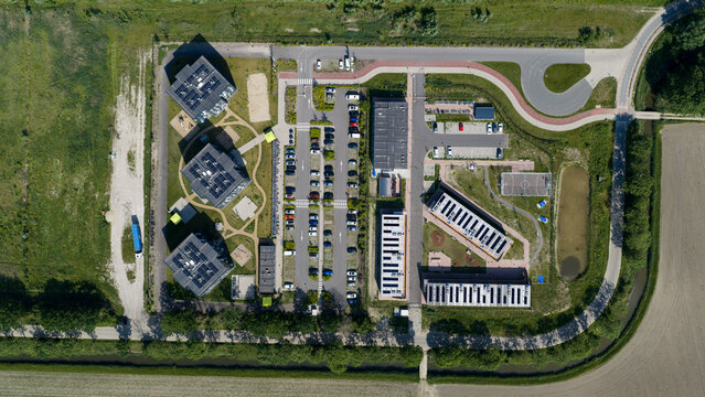 Aerial view of KaFra Zevenbergen featuring modern buildings with solar panels, a parking lot, and green spaces in Zevenbergen, Noord-Brabant, Netherlands.