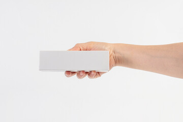Obraz premium A white product box in hand, against a white background. Packaging box.