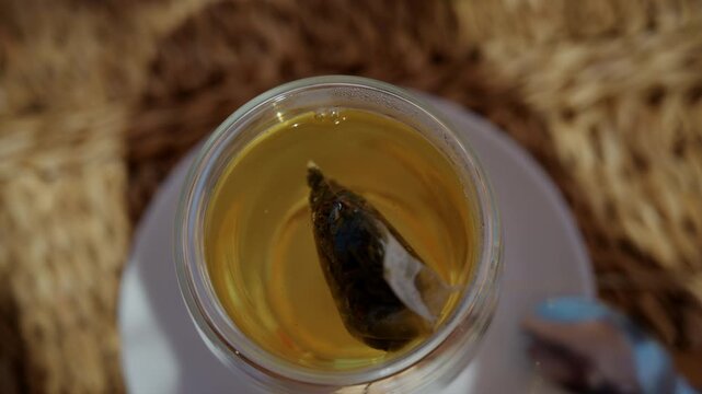 Close up of a tea bag steeping in hot water inside a transparent glass cup