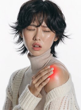 A young woman with a painful facial expression winces while clutching her aching shoulder, which features a prominent red glow effect to highlight localized joint and muscle inflammation 