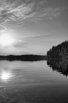Sunset over a lake with reflection and evening atmosphere, in black and white
