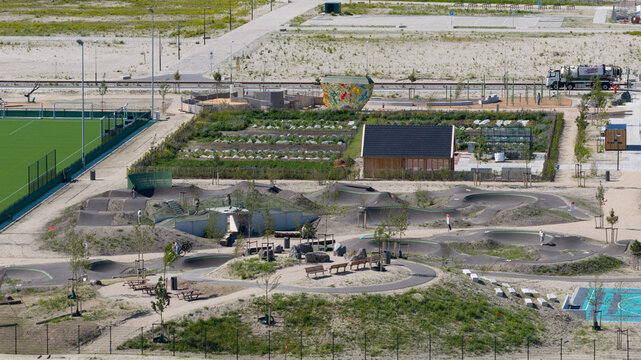 Aerial view of Sportpark Strandeiland featuring a pump track, football pitch, and community gardens in a modern urban development area Amsterdam, North Holland, Netherlands.