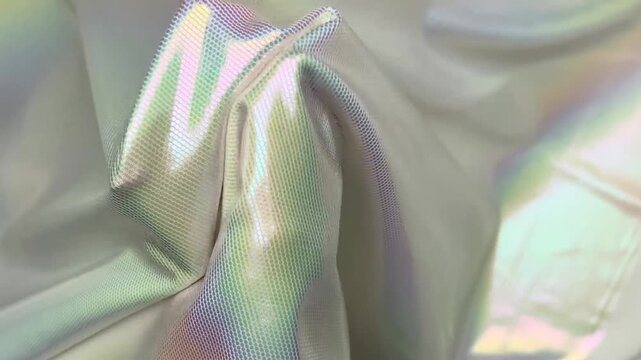 Shimmering stretch knit textile displaying an intense iridescent holographic effect with rainbow reflections, featuring an elastic texture suitable for unique fashion apparel projects.