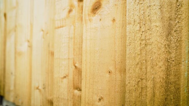 Wooden fence panels forming residential backyard boundary with natural timber texture. Fresh construction materials highlighting garden privacy screening and outdoor property improvement. Close up