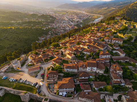 Aerial view of Berat Castle with its historic stone houses and red-tiled roofs overlooking the Osum river valley during sunset in Berat, Qarku i Beratit, Albania.