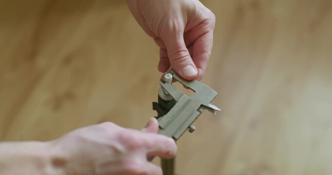 Close up view of hands measuring a thread diameter with a vernier caliper tool