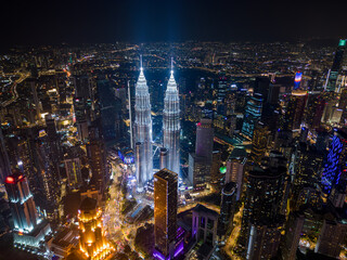 Fototapeta premium Aerial drone view of Kuala Lumpur downtown with illuminated skyscrapers and the city skyline at night, Malaysia.