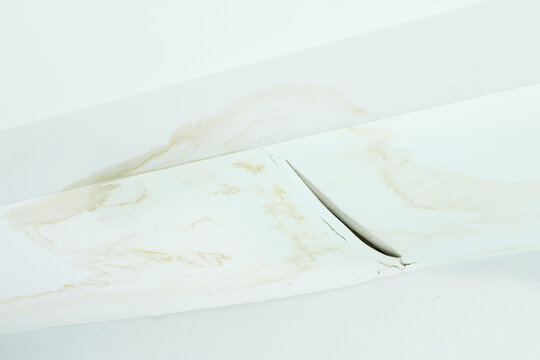 damaged ceiling with severe water stains, mold, and cracks caused by rain leaking through the roof. The image shows moisture damage and fungus growth from a ceiling leak problem water leaking ceiling